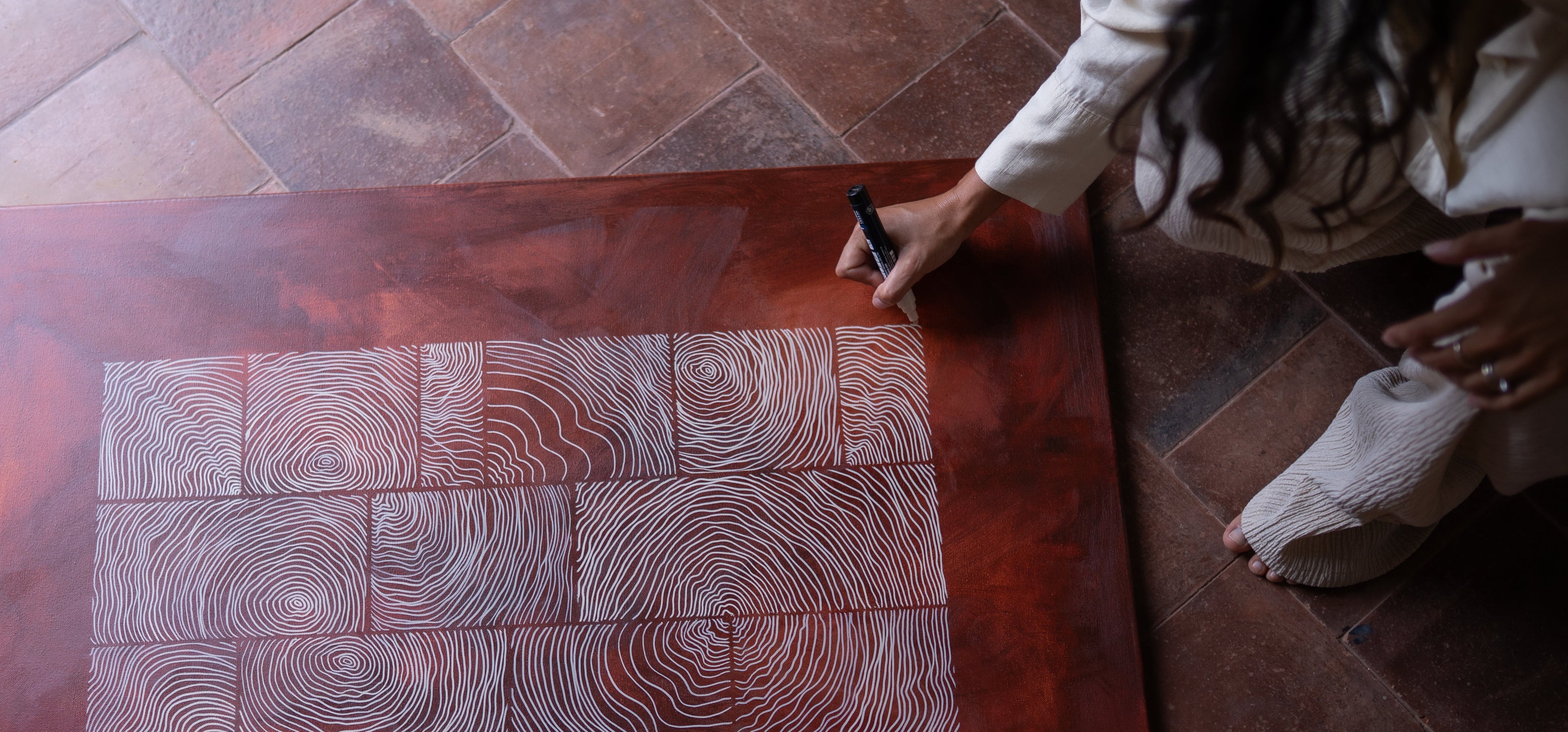 Person drawing on a large wooden panel with concentric circle patterns